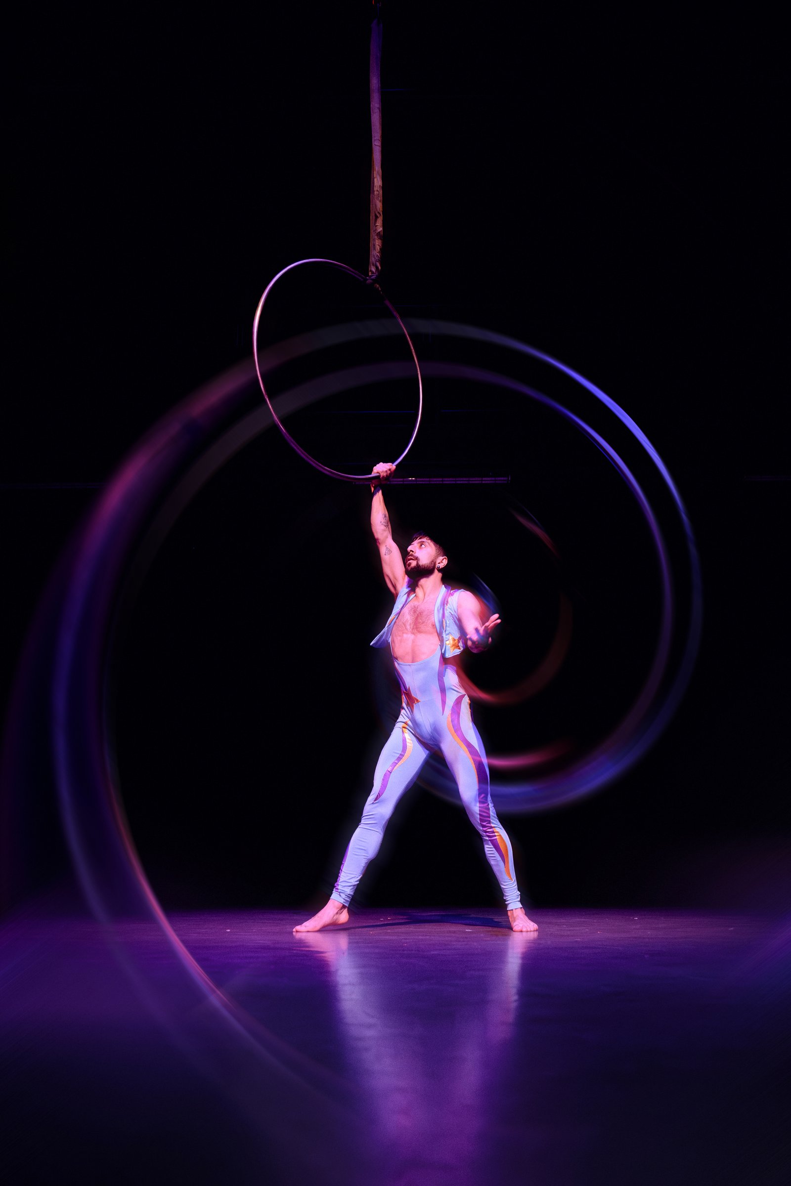 Hooman performing aerial hoop in violet light